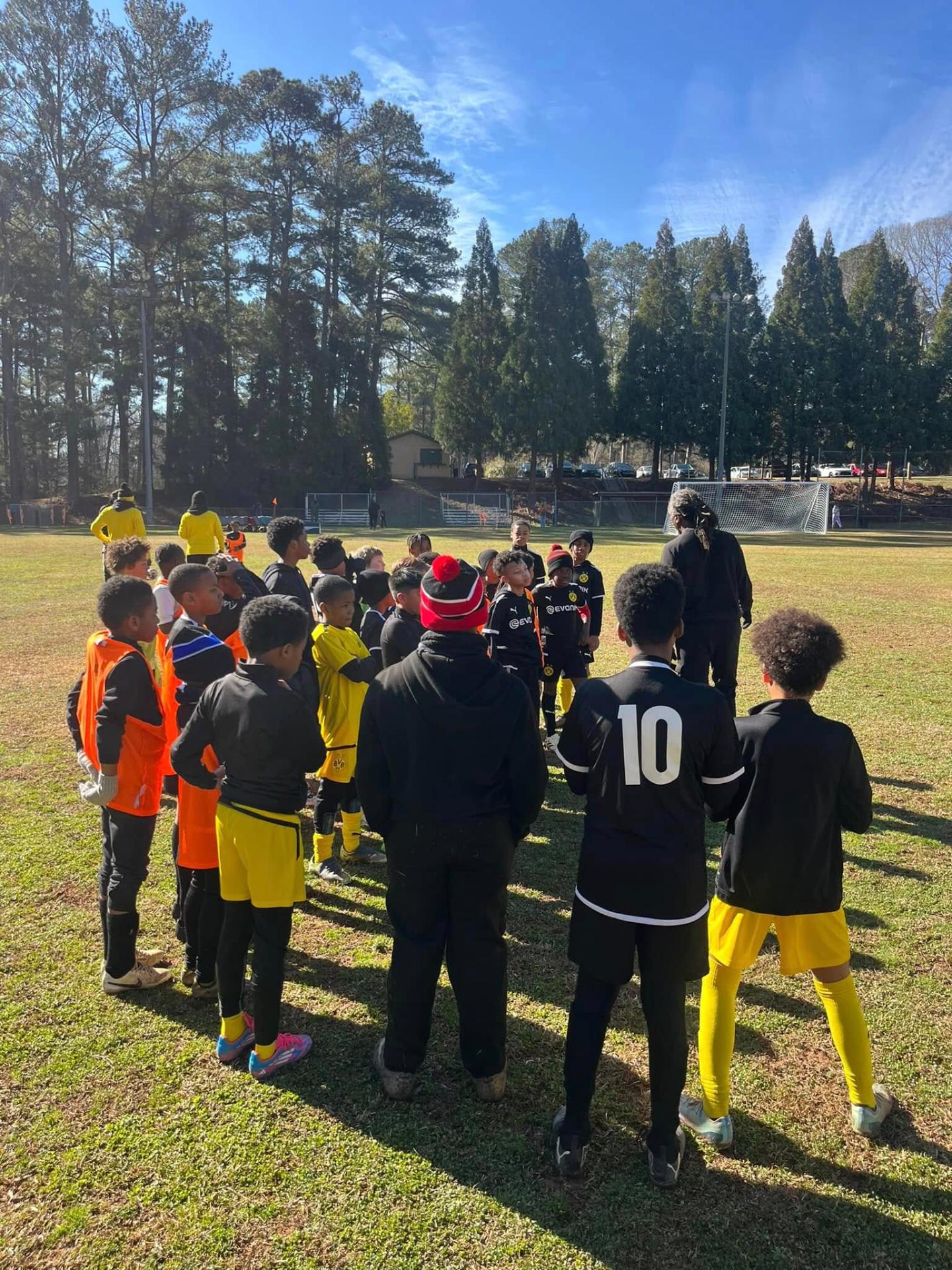 Youth players gathered for post-match talk on a sunny field