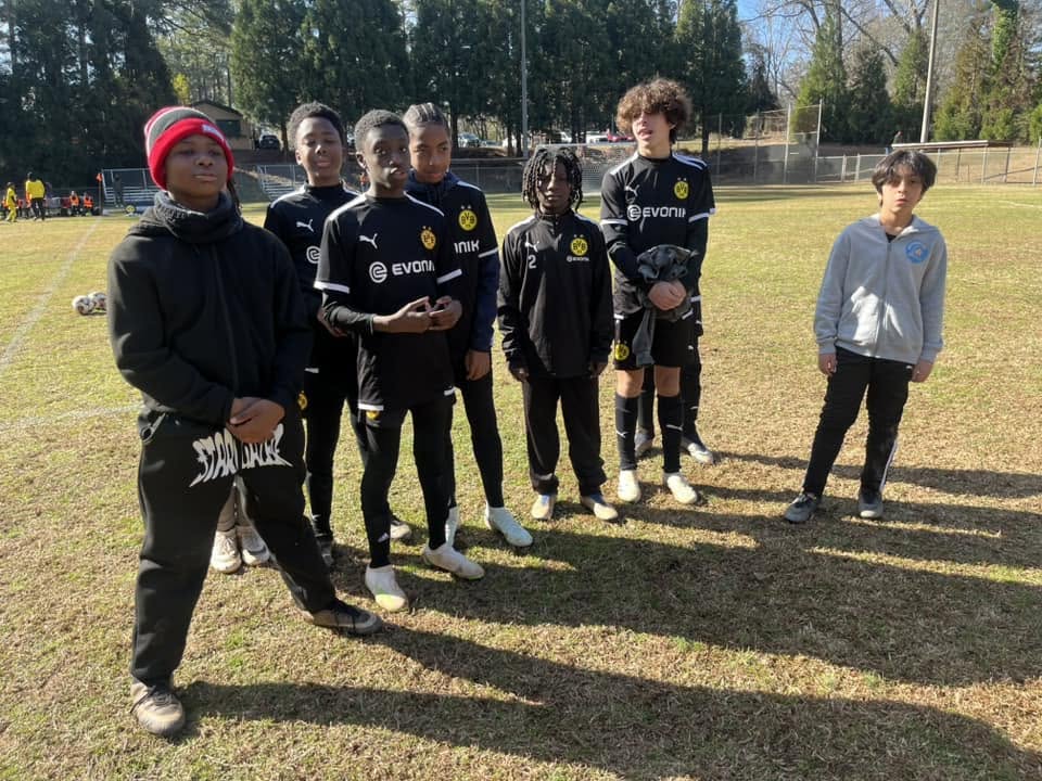Boys team in black Dortmund-style kits posing on the pitch