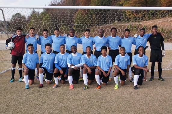 Youth team in light blue kits posed in front of the goal